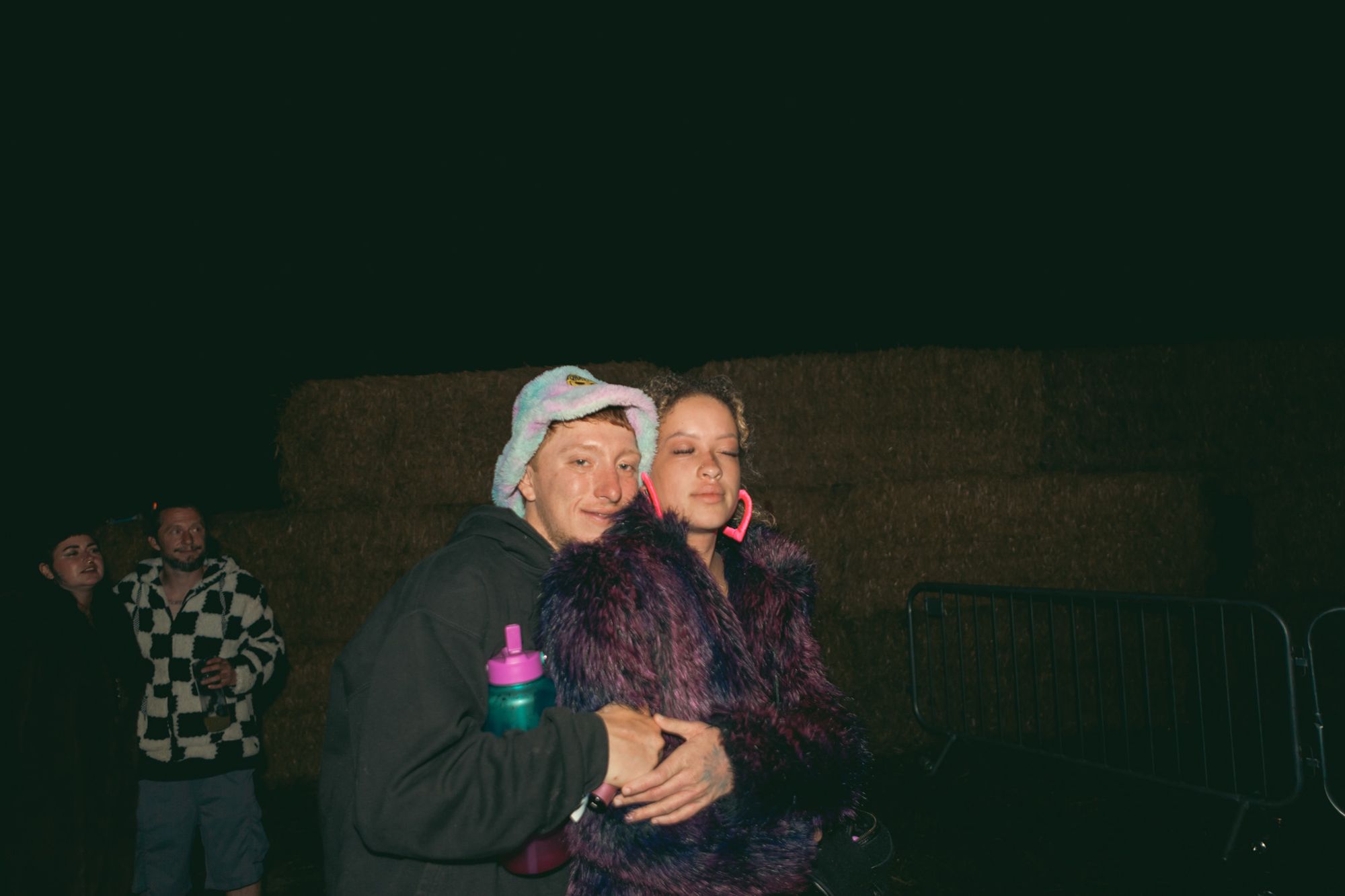 Couple hugging by the hay bales at night